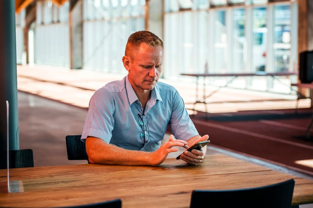 Mand sidder med sin telefon